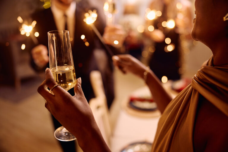 Close up of African American woman drinking champagne while celebrating New Year with her friends.