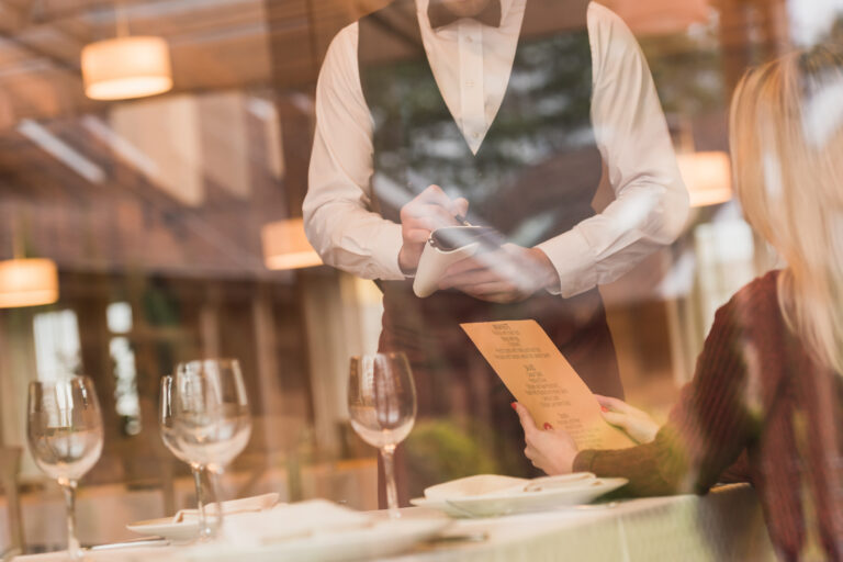 Cropped image through window of Waiter writing down the order of customer at the restaurant